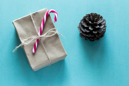 A paper parcel wrapped tied with a tag and candy cane. A christmas gift box wrapped with paper kraft with cone.
