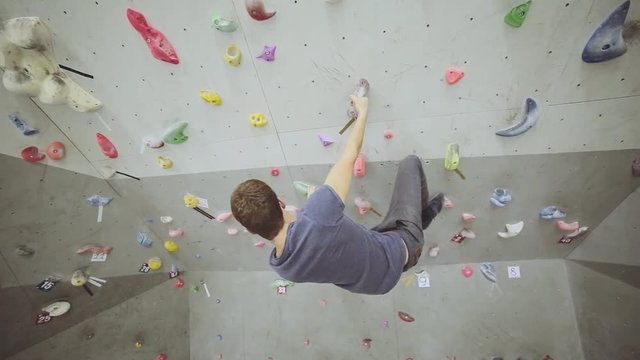 Free climber young man on artificial climbing wall rock in bouldering gym