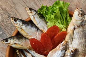 Salty stockfish on wooden table. Rainbow smelt, Common bream, Vobla, Shemay, Macrourus caviar and lettuce leaves.