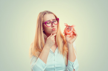 Woman holding piggy thinking