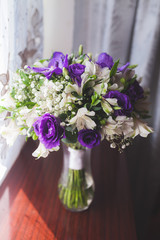 bride bouquet in the vase on wooden table, white violet colours