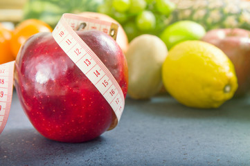 Apple and measuring tape over fruity background