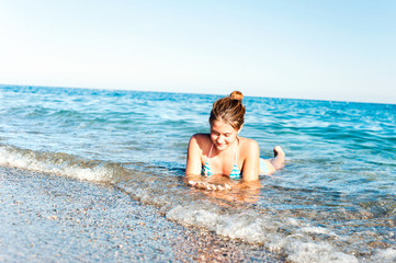 Happy young girl enjoying in sea splashing waves. Mediterranean