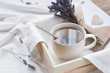 Un plateau avec une tasse de thé chaud et une lettre d& 39 amour à la lavande au lit