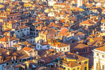 Aerial view of Venice, Italy, at sunset with rooftops of building, the sea and warm sunlight.