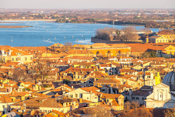 Aerial view of Venice, Italy, at sunset with rooftops of building, the sea and warm sunlight.