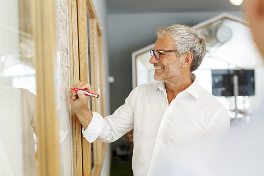 Businessman writing on board in office