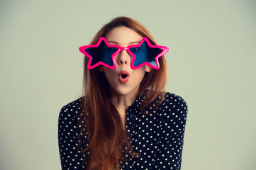 Portrait closeup Surprised young woman in star shaped sunglasses over green gray background
