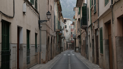 Fototapeta na wymiar empty narrow street in Soller Mallorca with typical historic houses on both sides and mountains in far distant background