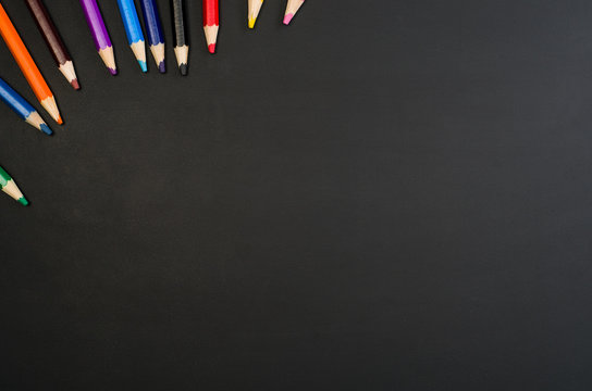 School supplies border on black chalkboard background. Top view product photograph with copy space for text or design. Back to school, education concept