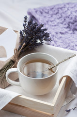 A tray with a cup of hot tea and lavender love letter in bed with a knitted blanket