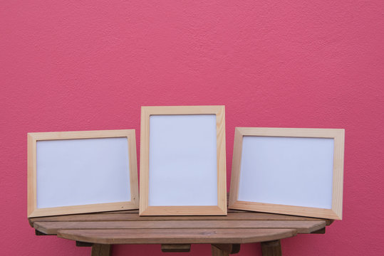 Three photo Frame on a wooden on pink background .
