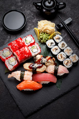Japanese cuisine. Sushi set on a stone plate and concrete background.