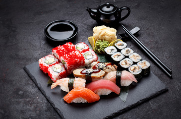 Japanese cuisine. Sushi set on a stone plate and concrete background.