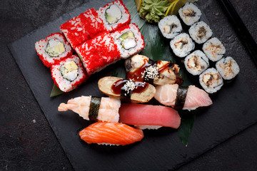 Japanese cuisine. Sushi set on a stone plate and concrete background.