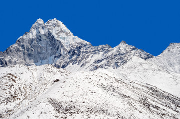 Fototapeta na wymiar Snowy peak over blue sky (Ama Dablam in the Everest Region)