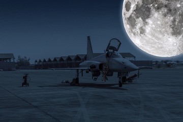 F-5E Aggressor Hornet fighter jet reflects the full moonlight. F-5 military aircraft parked in the airport at night sky with stars