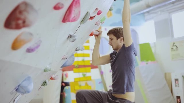Young strong man rock climbing indoors at the gym
