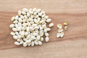 Yellow bowl of pistachios on wooden background
