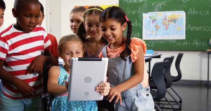 Schoolkids using digital tablet in classroom at school