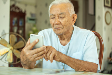 Happy asian senior man using the mobile phone at home