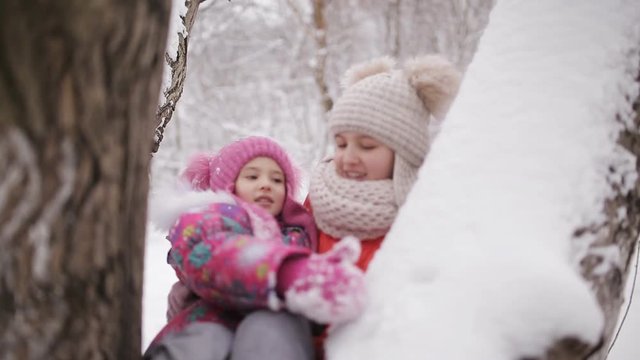 Little girls swinging on the branches of trees, snow-covered
