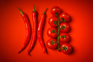 spicy peppers and small tomatoes on a red background