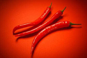 three spicy and fresh pepper on a red background