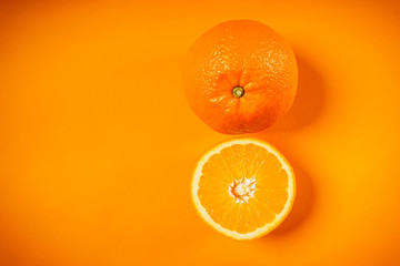 Two fresh and juicy oranges on an orange background