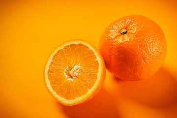 Two fresh and juicy oranges on an orange background