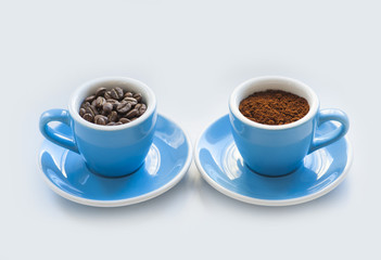 two blue macro coffee espresso cups with the fresh coffee beans and with a ground coffee on the white background