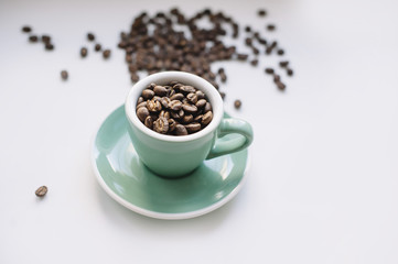 fresh morning coffee beans in a small espresso cup on a white background