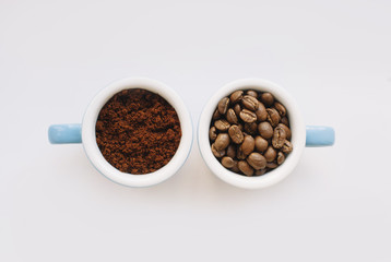two blue macro coffee espresso cups with the fresh coffee beans and with a ground coffee on the white background