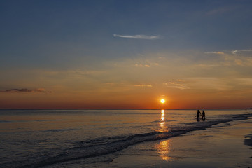 A couple wading in the Gulf of Mexico enjoying the sunset in Miramar Beach, Florida