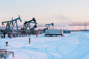Oil Field. Winter industrial landscape with an oil pump and torch in the background.