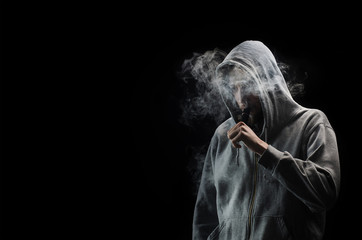 One man in the hood vaping e-cigarette and blowing a cloud.