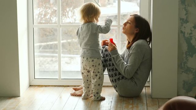 Mother and daughter blowing bubbles indoor