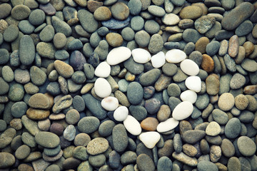 Heart of stones on a background sea pebbles