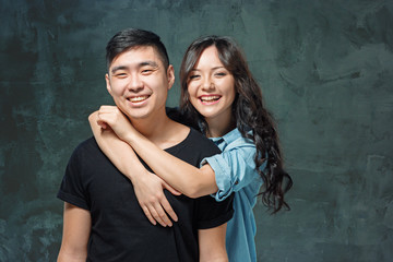 Portrait of smiling Korean couple on a gray