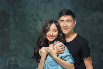 Obraz na płótnie Canvas Portrait of smiling Korean couple on a gray
