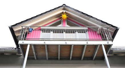 Moderner Haus-Giebel mit Stahl-Balkon. Ziegeldach und Weihnachtsstern
