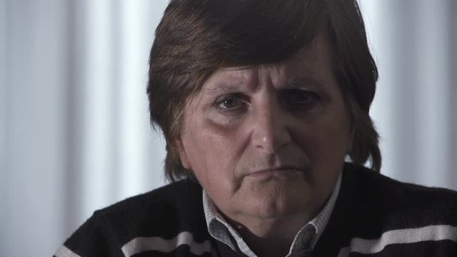 Very angry elderly woman looks at the camera contemptuously