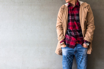 Men's casual outfits wear blue jeans with red plaid shirt and brown coat standing over gray grunge...