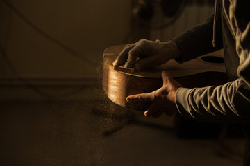 Serious professional guitar-maker working with unfinished guitar at workshop