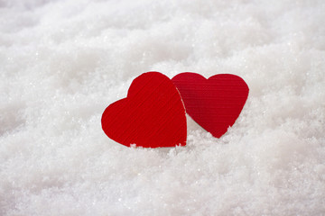 Obraz premium Two red hearts in snow