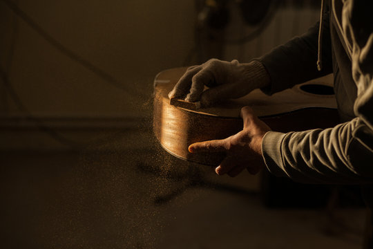 Serious professional guitar-maker working with unfinished guitar at workshop