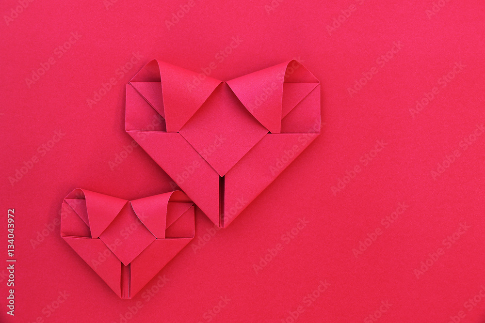 Poster two folding red paper hearts on red for pattern and background