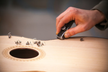 Serious professional guitar-maker working with unfinished guitar at workshop