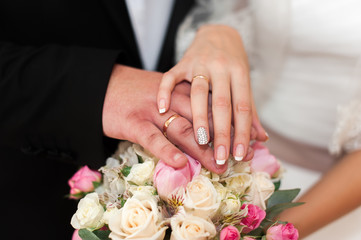 Obraz na płótnie Canvas Hands of newlyweds with rings on unusual wedding bouquet.