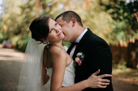 Elegant young happy wedding couple is sitting at green grass on